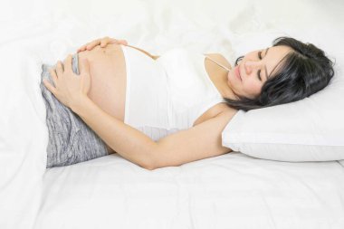 Hamilelik, dinlenme, insanlar ve beklenti konsepti. Mutlu Asyalı hamile kadın evde huzur içinde uyuyor..