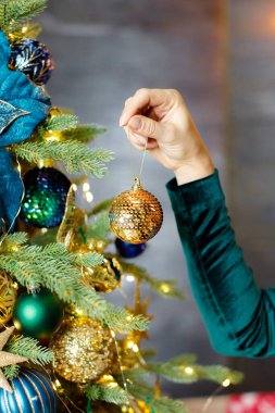 Süslü bir Noel ağacının arka planında bir kadeh şampanya tutuyor.