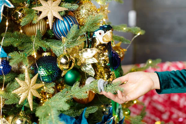 Süslü bir Noel ağacının arka planında bir kadeh şampanya tutuyor.