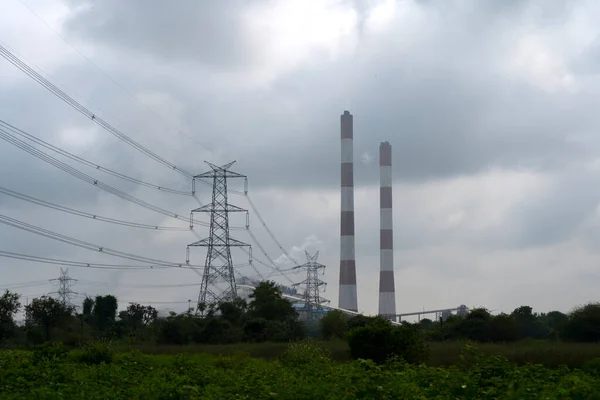 Bulutlu arka planda endüstriyel boruları olan elektrik hatları