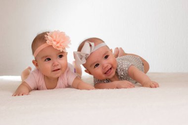 baby twins lying in bed with bow on head
