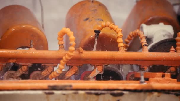 Cierre la toma de la máquina de color naranja que salpica el agua en una cámara lenta de fábrica — Vídeo de stock