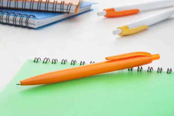 Bolígrafo plástico naranja con cuaderno verde —  Fotos de Stock