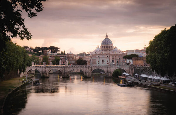 Tourist and Postcard View of St Angelo Bridge with Vatican and St Peters Basilica under Sunset Sky in Rome, Italy