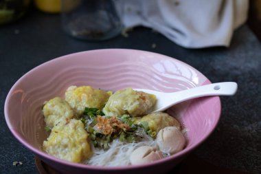 Pork wonton noodle, siyah arka plan masasında beyaz vermicelli.
