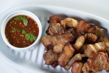 Balık soslu kızarmış domuz eti ve beyaz tabakta baharatlı sos.