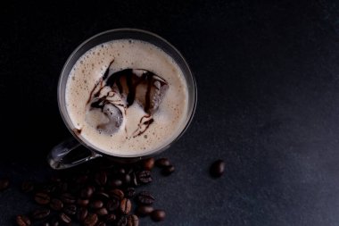 Siyah arka planda berrak bir bardakta buzlu kahve..