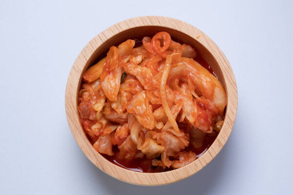 Lettuce kimchi in wooden cup on white background
