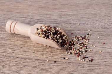 Ahşap bir arka planda, ahşap bir kaşıkta kinoa ve çeşitli vitaminler ve mineraller..