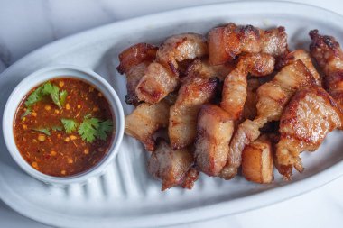 Balık soslu kızarmış domuz eti ve beyaz tabakta baharatlı sos.