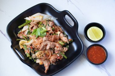 Kurutulmuş sukiyaki ve siyah tabakta domuz eti ve sukiyaki sosu.