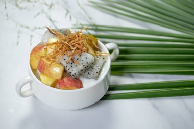 Beyaz bir fincanda karışık meyve yoğurdu.