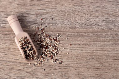 Ahşap bir arka planda, ahşap bir kaşıkta kinoa ve çeşitli vitaminler ve mineraller..