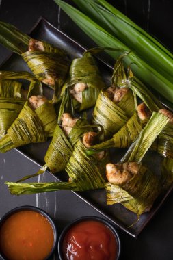 Pandana sarılmış kızarmış tavuk siyah bir tabakta.