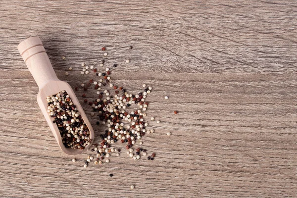 Ahşap bir arka planda, ahşap bir kaşıkta kinoa ve çeşitli vitaminler ve mineraller..