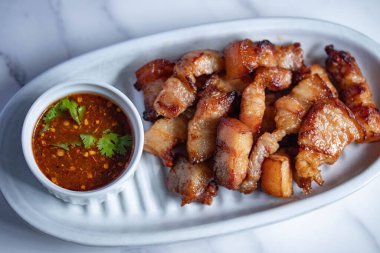 Balık soslu kızarmış domuz eti ve beyaz tabakta baharatlı sos.