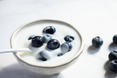 Beyaz fincanda mermer zemin üzerinde taze yaban mersinli yoğurt