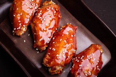 Baharatlı ve tatlı Kore soslu kızarmış tavuk kanadı üzerine beyaz susam tohumu.