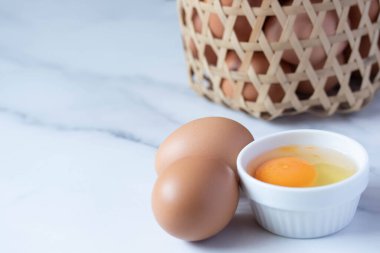 Fresh chicken eggs in a white ceramic cup.