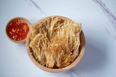 Beyaz tabakta baharat soslu çıtır altın iğneli mantar.