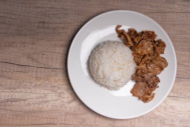 Beyaz tabakta sarımsaklı ve biberli kızarmış domuz eti.