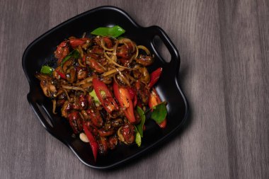 Siyah bir tabakta baharatlı kızarmış midye. Tayland yemeği.