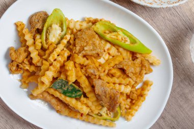 Kırmızı köri ezmeli kızarmış domuz eti ve beyaz tabakta taze hindistan cevizi filizleri.