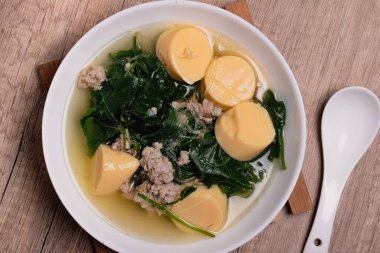 Tahta arka plandaki Tayland yemeğinin üzerinde kıymalı domuz eti ve yumurtalı tofu ile sebze çorbası. (gaeng jued tum luang)