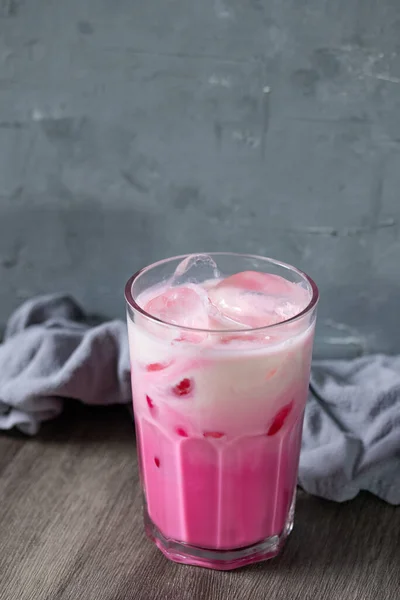 cold pink milk cold drink in clear glass on gray background. Thai milk