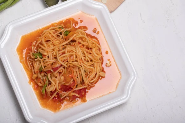 Beyaz tabakta Tayland papaya salatası. Beyaz arka planda popüler yemekler.