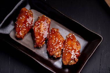 Baharatlı ve tatlı Kore soslu kızarmış tavuk kanadı üzerine beyaz susam tohumu.