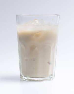 Beyaz arka planda berrak bir bardakta soğuk taze süt.