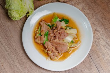 Beyaz tabakta kızarmış lahana ve domuz eti.