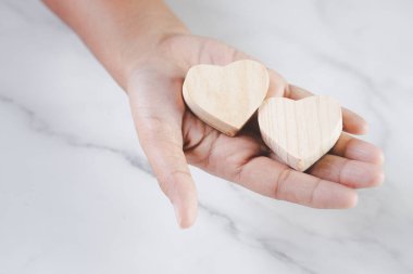 Elinde ahşap bir kalp var. Sağlıklı bir kalbi sürdürme kavramı.
