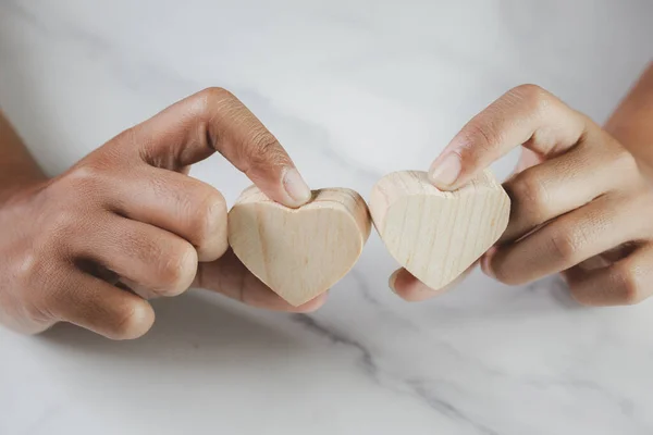 There is a wooden heart in the hand. The concept of maintaining a healthy heart.