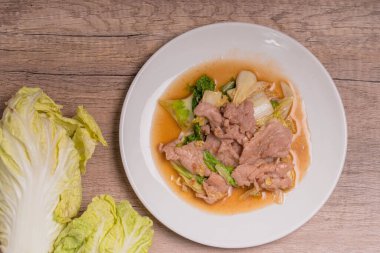 Beyaz tabakta kızarmış lahana ve domuz eti.