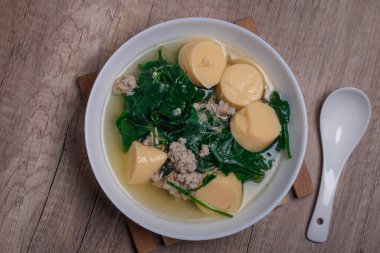 Tahta arka plandaki Tayland yemeğinin üzerinde kıymalı domuz eti ve yumurtalı tofu ile sebze çorbası. (gaeng jued tum luang)