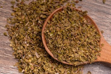 Tahta bir arka planda tahta bir kaşıkta keklik otu.