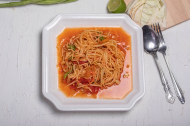 Beyaz tabakta Tayland papaya salatası. Beyaz arka planda popüler yemekler.