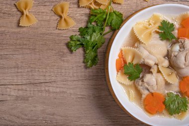 Tavuk butlu makarna çorbası, havuçlu temiz et suyu. Köhne ahşap arka planda..