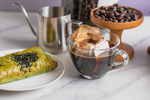 Drip coffee in a bag, drip in a clear coffee mug.