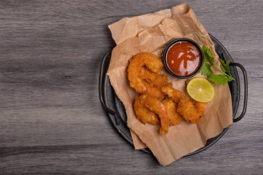 Breaded and breaded shrimp with chilli sauce on black background
