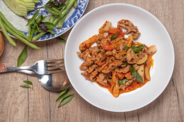 Pork stir fried in chili paste with tomatoes and onions in a white dish