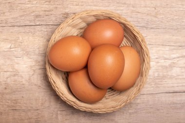 Tahta arka planda bambu sepetinde tavuk yumurtası.