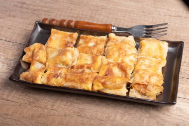 Crispy roti topped with milk in a black plate
