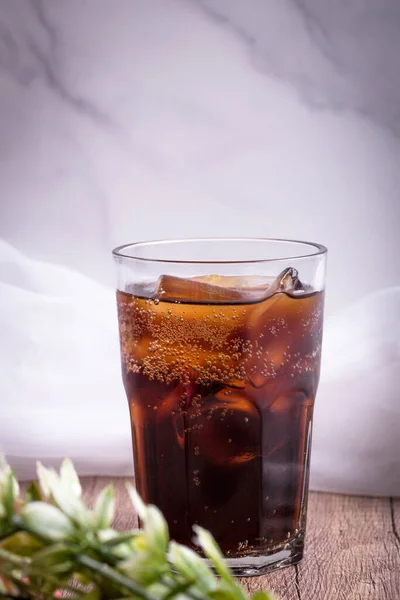 cola cola drink with ice in glass put on wooden background
