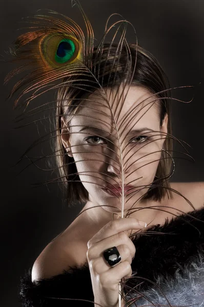 Young woman holding peacock feather — Stock Photo, Image