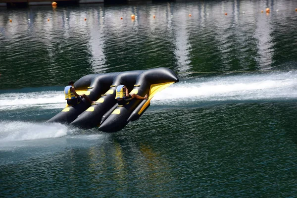 Un radeau de sport gonflable avec deux hommes flotte rapidement dans l'eau, se détachant presque de lui — Photo