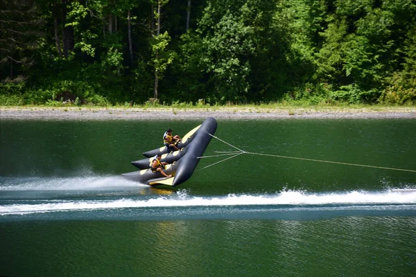 An inflatable sports raft with two men quickly floats through the water, almost breaking away from it — Stock Photo, Image