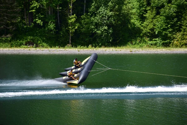 Un radeau de sport gonflable avec deux hommes flotte rapidement dans l'eau, se détachant presque de lui — Photo